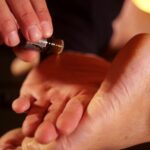 Applicazione di olio essenziale sui piedi per un trattamento di riflessologia plantare